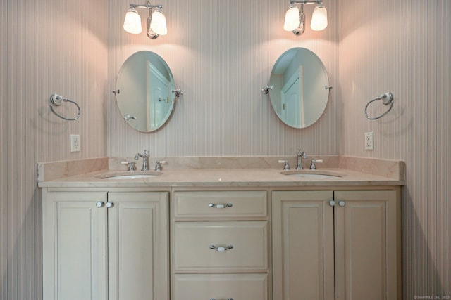 full bath featuring double vanity, a sink, and wallpapered walls