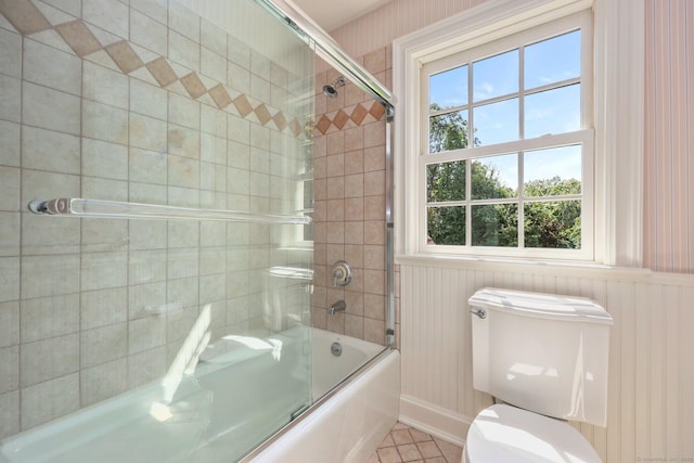 bathroom with combined bath / shower with glass door and toilet