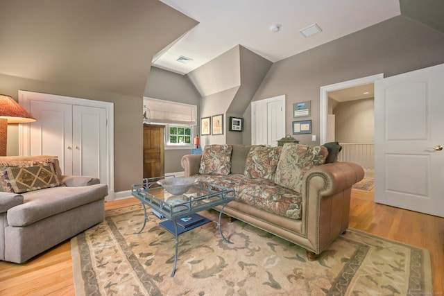 living area with lofted ceiling, light wood-style flooring, and visible vents