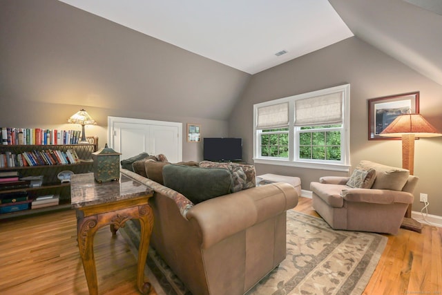 living area with light wood finished floors, baseboards, visible vents, and vaulted ceiling