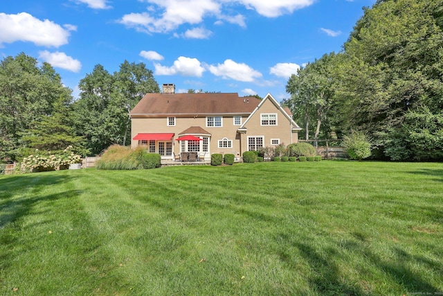 back of house with a lawn and a chimney