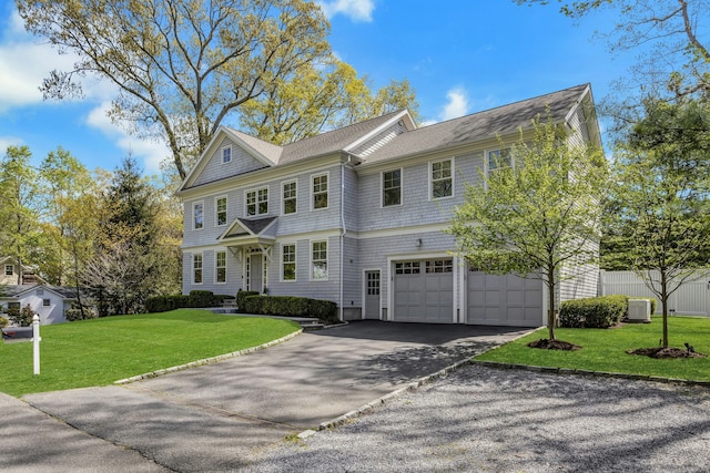 view of front facade featuring an attached garage, cooling unit, aphalt driveway, a shingled roof, and a front yard