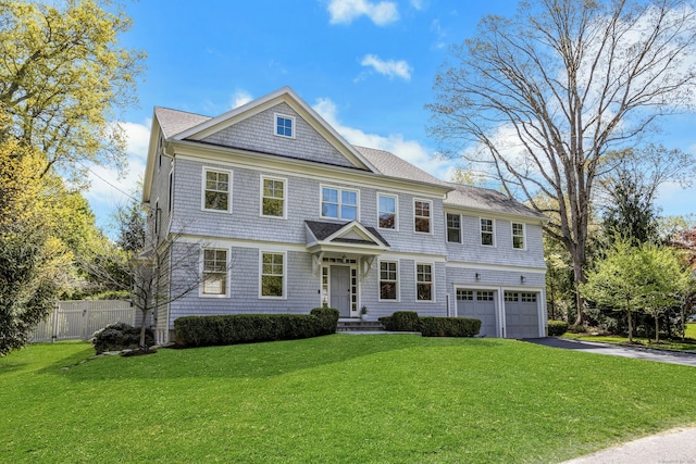 shingle-style home featuring driveway, a garage, fence, and a front yard