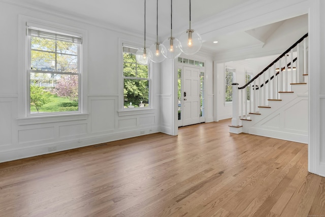 entrance foyer featuring stairway, ornamental molding, a decorative wall, and visible vents