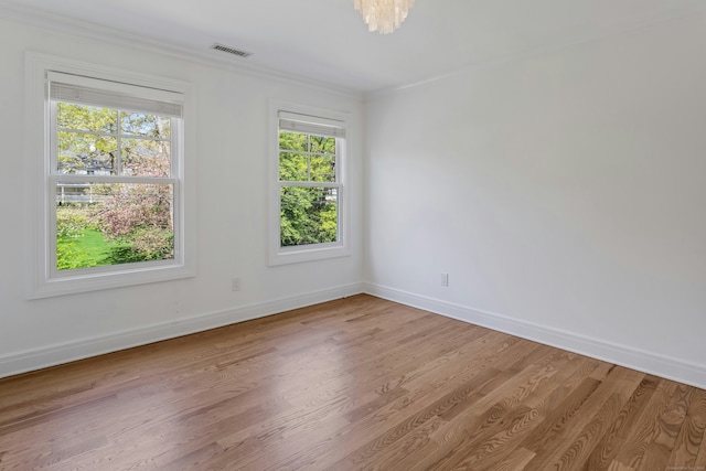 spare room with baseboards, crown molding, visible vents, and light wood-style floors