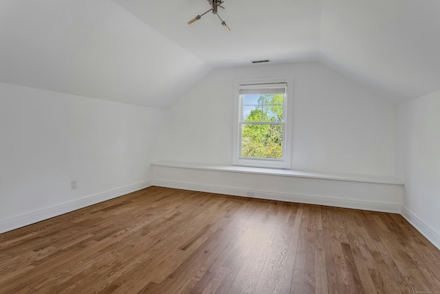 bonus room with baseboards, wood finished floors, visible vents, and vaulted ceiling