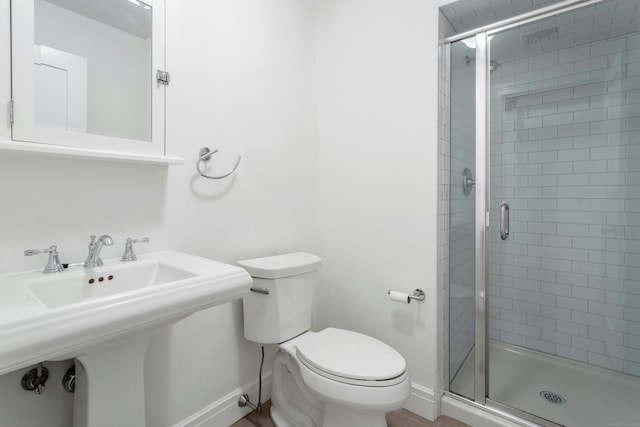 full bathroom with a stall shower, toilet, and baseboards