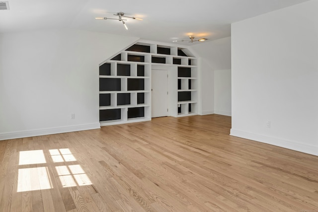 additional living space featuring vaulted ceiling, baseboards, and light wood-type flooring