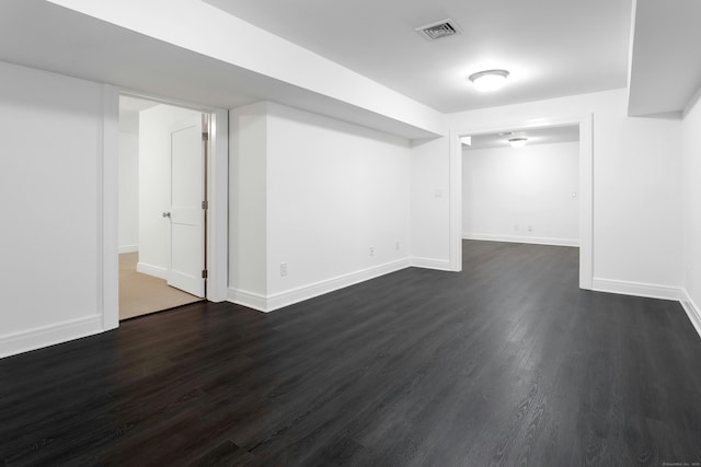 finished basement with baseboards, dark wood-type flooring, and visible vents