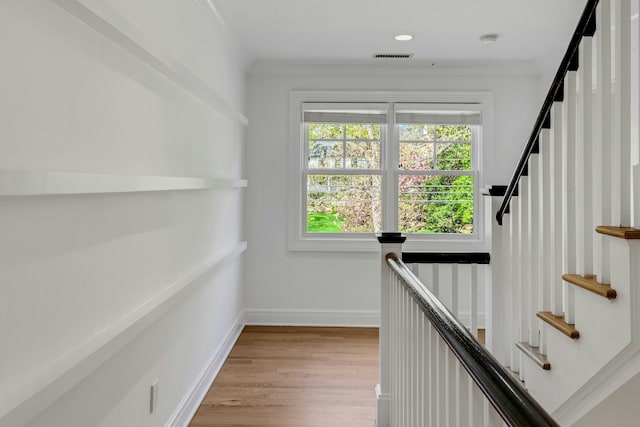 hallway with visible vents, stairway, light wood finished floors, crown molding, and baseboards