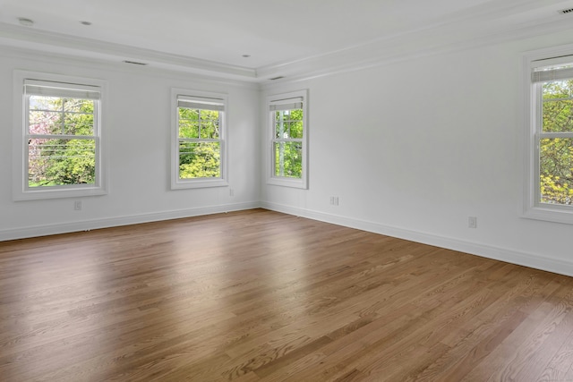 spare room with baseboards, visible vents, crown molding, and wood finished floors
