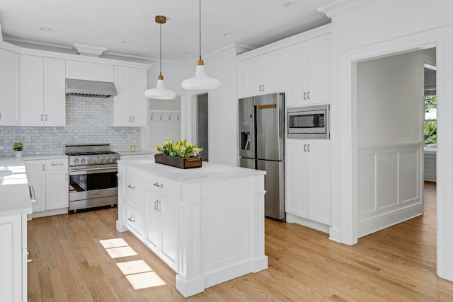 kitchen with under cabinet range hood, light wood finished floors, white cabinetry, backsplash, and appliances with stainless steel finishes