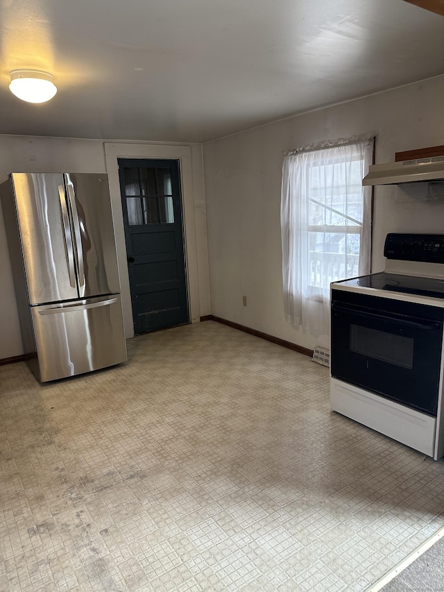 kitchen featuring electric stove, light floors, freestanding refrigerator, under cabinet range hood, and baseboards