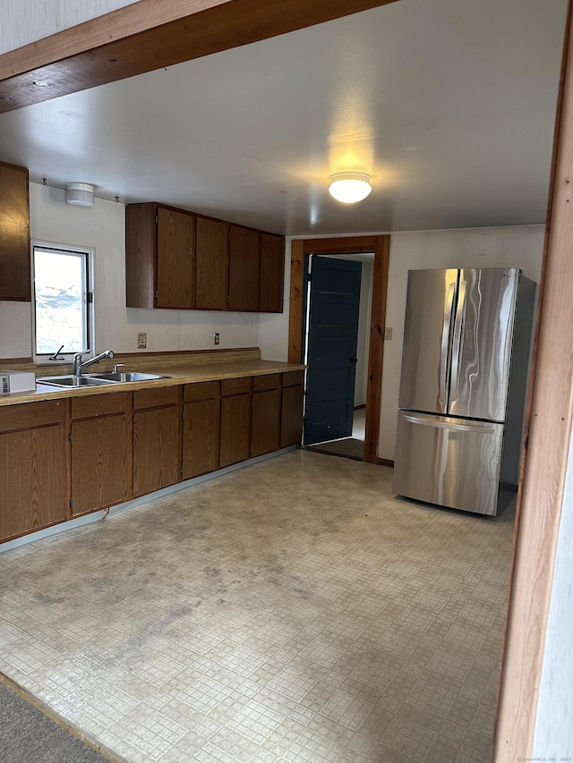 kitchen featuring freestanding refrigerator, light countertops, a sink, and light floors