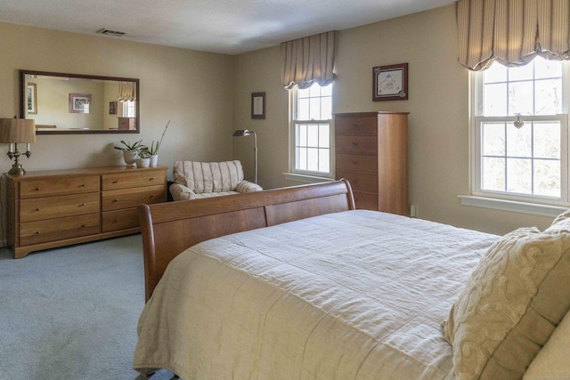 carpeted bedroom featuring visible vents and multiple windows