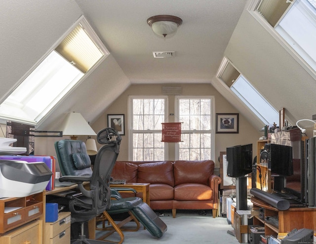 carpeted home office featuring lofted ceiling with skylight and visible vents