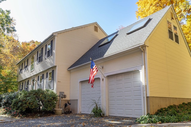 view of side of property with a garage and roof with shingles