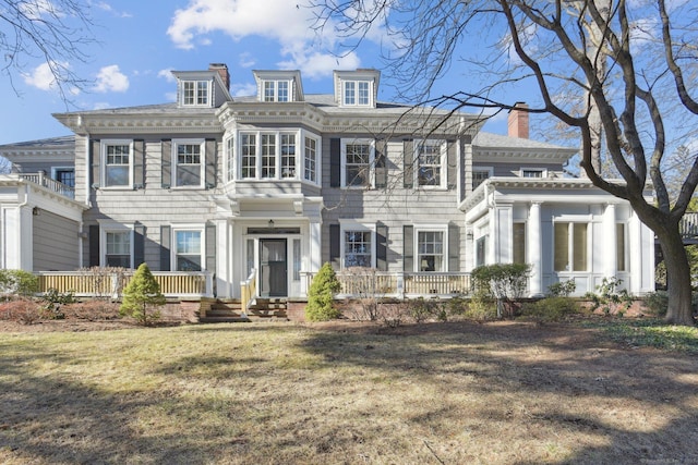 colonial-style house featuring a chimney and a front lawn