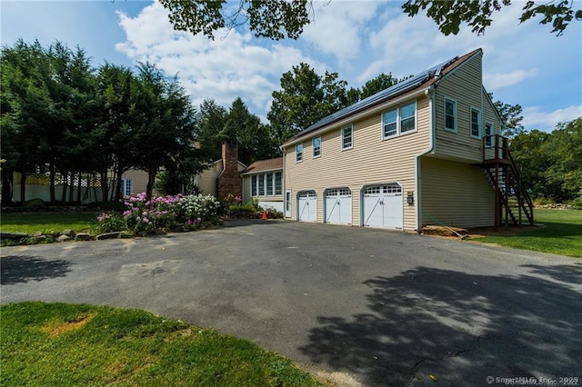 view of side of home featuring a garage, stairs, and aphalt driveway