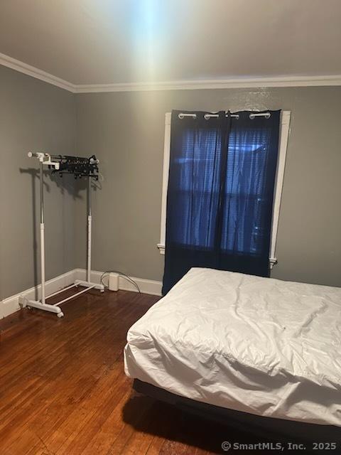 bedroom with crown molding, baseboards, and wood finished floors