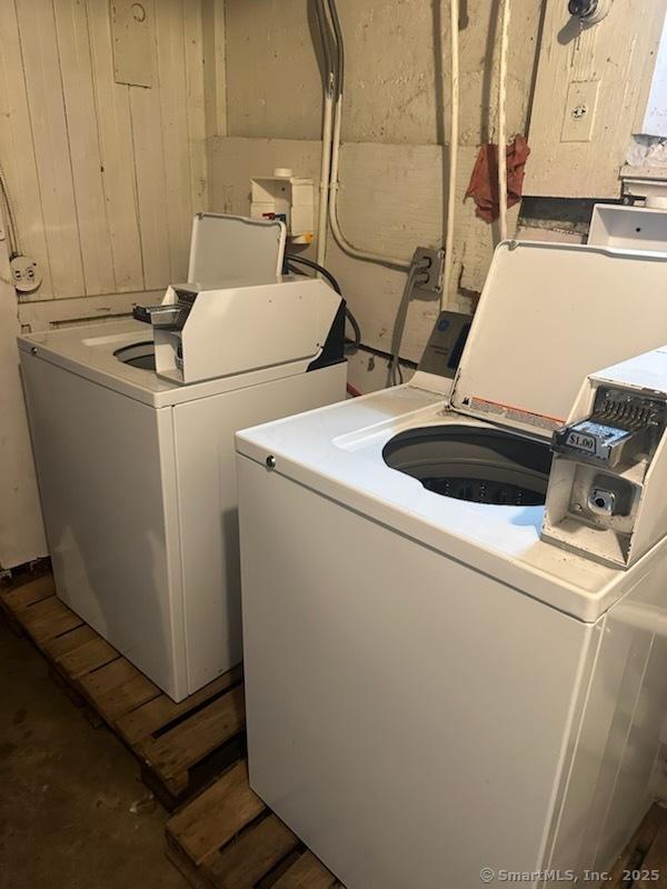 clothes washing area featuring wood walls and washer and dryer