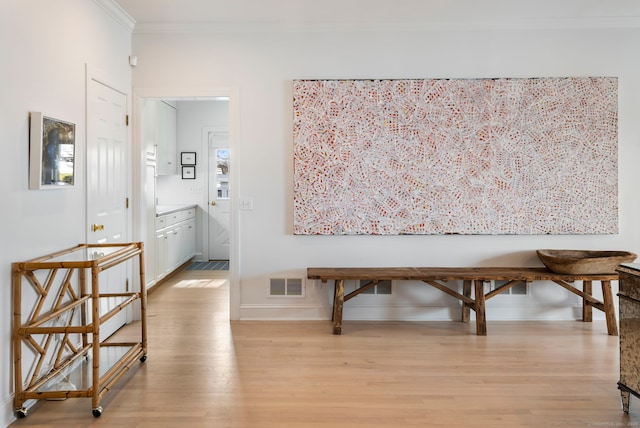 dining area featuring baseboards, light wood-style flooring, visible vents, and crown molding