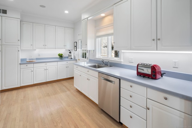 kitchen with light countertops, light wood-style flooring, white cabinetry, a sink, and dishwasher