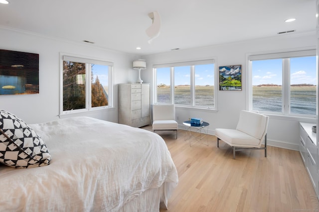 bedroom featuring visible vents, baseboards, wood finished floors, and ornamental molding