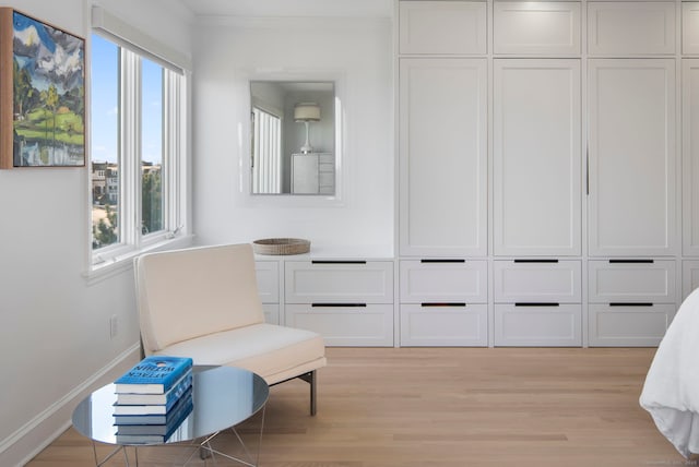 living area with light wood-type flooring, baseboards, ornamental molding, and a wealth of natural light