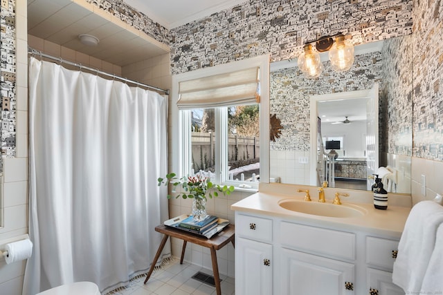 full bathroom with wallpapered walls, a ceiling fan, tile patterned flooring, vanity, and tile walls