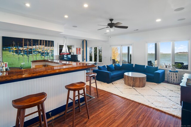 interior space featuring recessed lighting, a ceiling fan, open floor plan, wood finished floors, and a kitchen bar