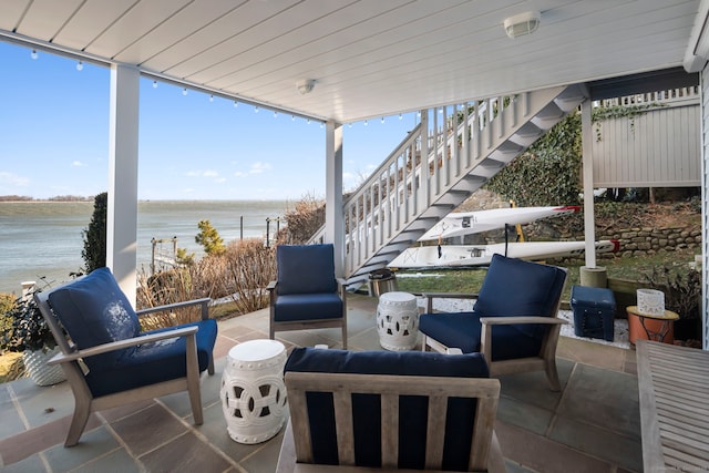 view of patio / terrace with a water view, stairway, and outdoor lounge area