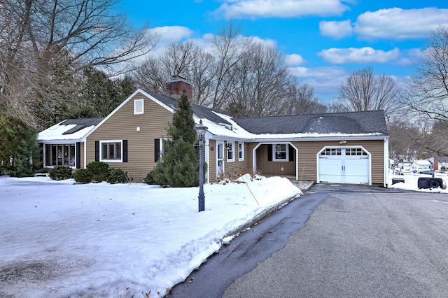 ranch-style house with an attached garage, a shingled roof, a chimney, and aphalt driveway