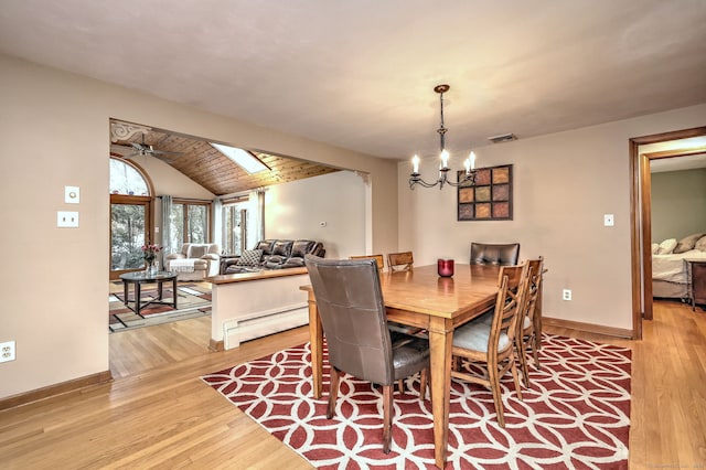 dining area featuring vaulted ceiling, light wood-type flooring, a baseboard radiator, and baseboards