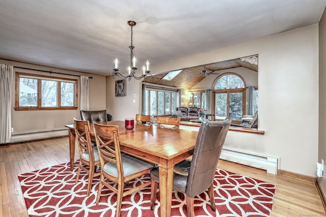 dining area featuring light wood finished floors, vaulted ceiling, baseboards, and baseboard heating