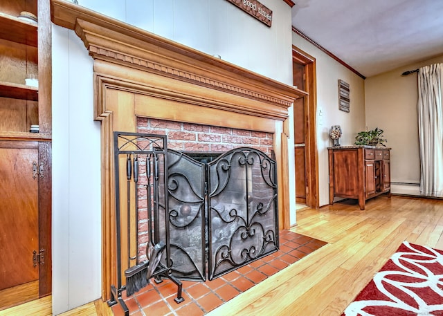 interior details featuring crown molding, a fireplace, baseboard heating, and wood finished floors