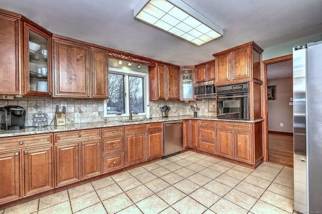 kitchen featuring appliances with stainless steel finishes, light tile patterned flooring, glass insert cabinets, and light stone countertops