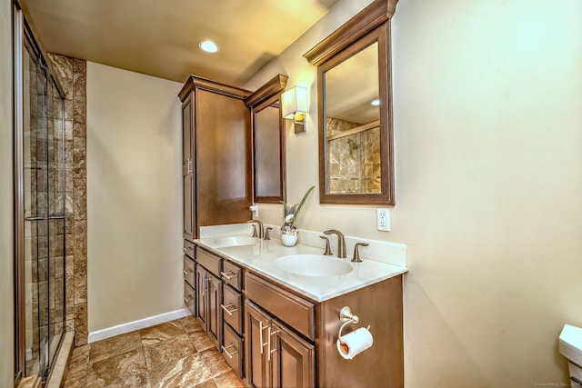 full bathroom with double vanity, baseboards, a sink, and tiled shower