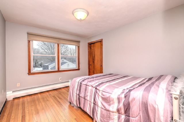 bedroom featuring a baseboard radiator, a closet, and light wood-style flooring