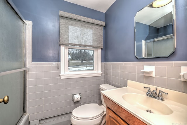 bathroom with toilet, a wainscoted wall, tile walls, and vanity