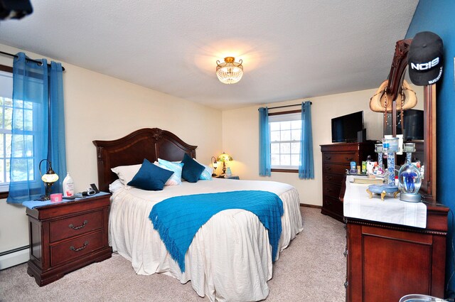 bedroom with baseboard heating and light colored carpet