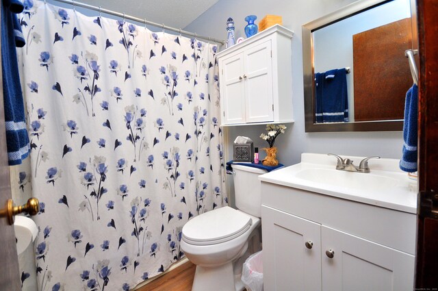 bathroom with toilet, a shower with curtain, wood finished floors, and vanity