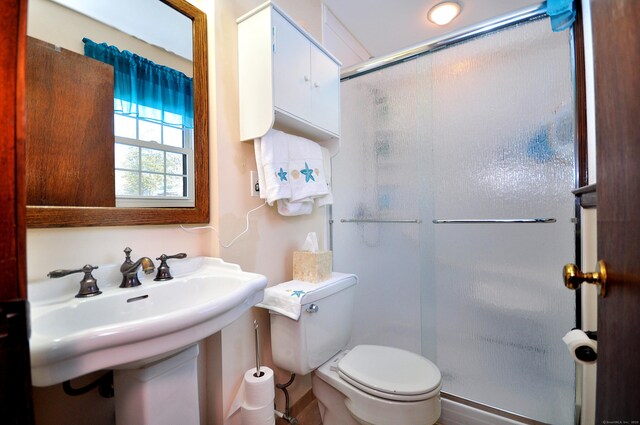 full bathroom featuring a stall shower, a sink, and toilet