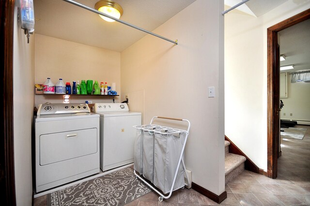 clothes washing area featuring washer and dryer, laundry area, baseboards, and a baseboard radiator