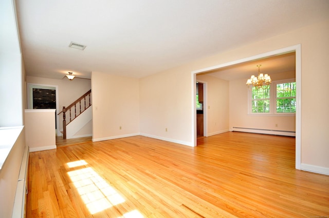 unfurnished living room with a baseboard heating unit, a chandelier, light wood-style floors, stairway, and baseboards