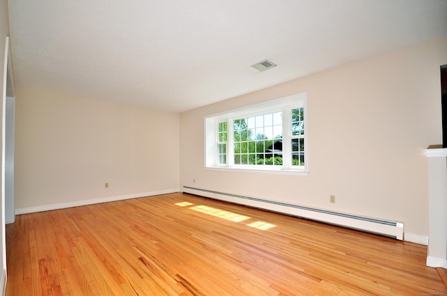 spare room featuring baseboard heating, wood finished floors, and baseboards