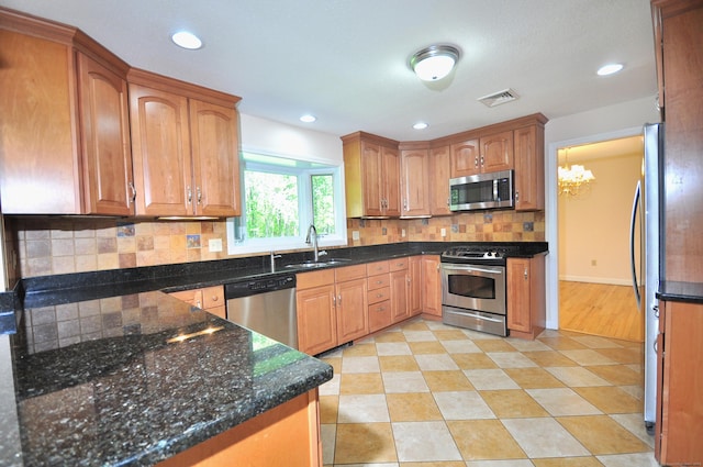 kitchen featuring stainless steel appliances, tasteful backsplash, a sink, dark stone countertops, and recessed lighting