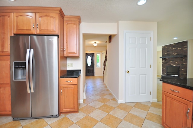kitchen with stainless steel fridge, light tile patterned floors, dark stone counters, recessed lighting, and baseboards