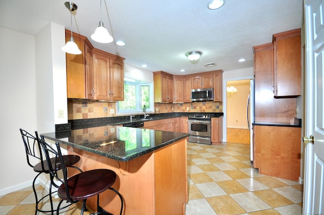 kitchen with appliances with stainless steel finishes, a peninsula, tasteful backsplash, a breakfast bar area, and decorative light fixtures