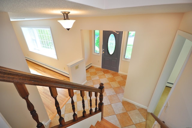 foyer with a baseboard heating unit, stairs, and baseboards